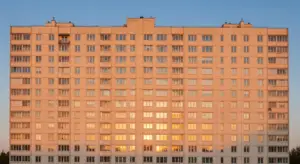 Large beige apartment building with many evenly spaced windows, bathed in warm sunset light.